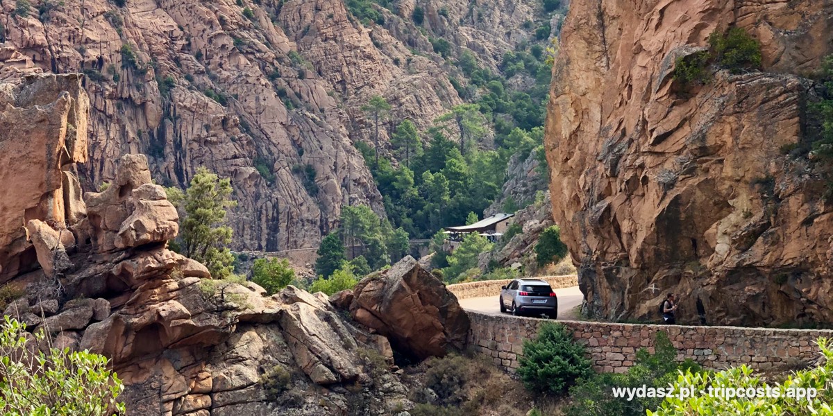 Samochód na wąskiej drodze wśród czerwonych skał Calanques de Piana na Korsyce