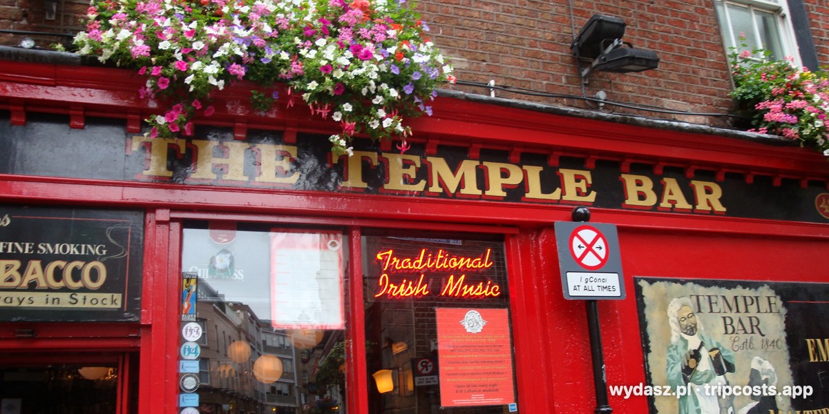 Czerwona fasada pubu The Temple Bar w Dublinie z kwiatami nad szyldem
